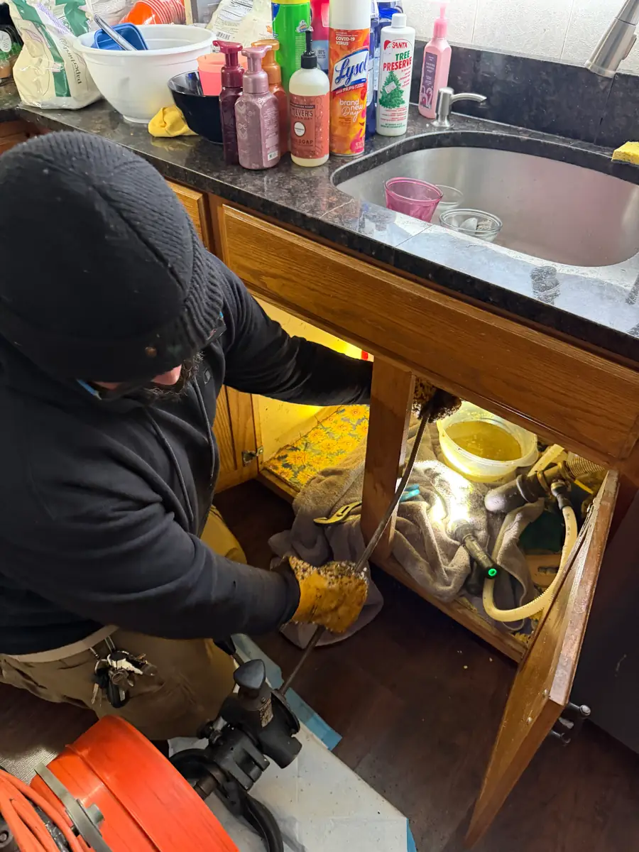 Drain machine set up under a kitchen sink with a towel down to protect the cabinet