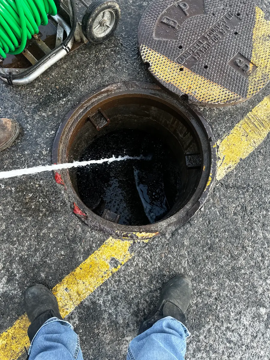 Hydro jetting hose running into an open sewer manhole